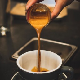 An espresso shot being poured into a coffee cup