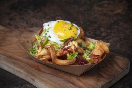 French fries topped with multiple toppings including green onions and a cooked egg.