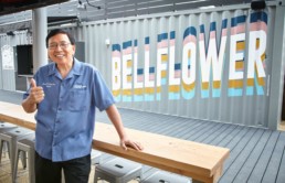 The Mayor of Bellflower poses with a smile and a thumbs-up in front of a steel container with 